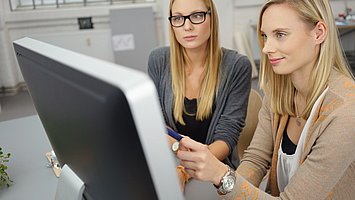 Hier sieht man zwei Frauen, die auf den PC-Bildschirm schauen