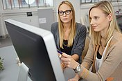 Hier sieht man zwei Frauen, die auf den PC-Bildschirm schauen
