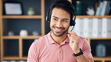 Ein Mann sitzt vor dem Laptop und telefoniert