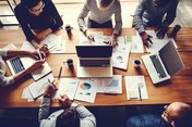 Junior-Brand-Manager (w/m/d) gesucht Eine Gruppe von Menschen sitzt um einen Tisch herum und arbeitet