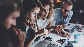 Teamwork Mehrere Menschen sitzen nebeneinander und arbeiten im Team zusammen